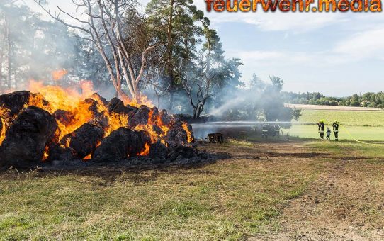 Brand von Strohrundballen und Brennholzlager droht sich auf Wald auszubreiten