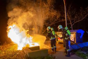 Passanten entfernen mehrer Mülltonnen von einer brennenden Müllinsel