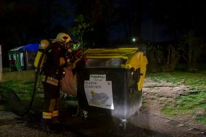 Passanten entfernen mehrer Mülltonnen von einer brennenden Müllinsel