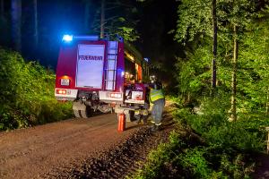 Traktor mit Heuballenpresse stürzt von einem Forstweg in den Wald