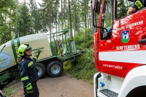 Traktor mit Heuballenpresse stürzt von einem Forstweg in den Wald